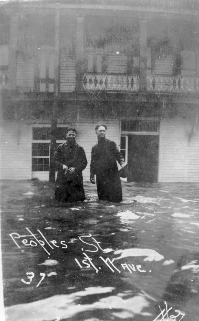 Two men standing knee deep in water before a home on Peoples Street in Corpus Christi after the hurricane of 1919.