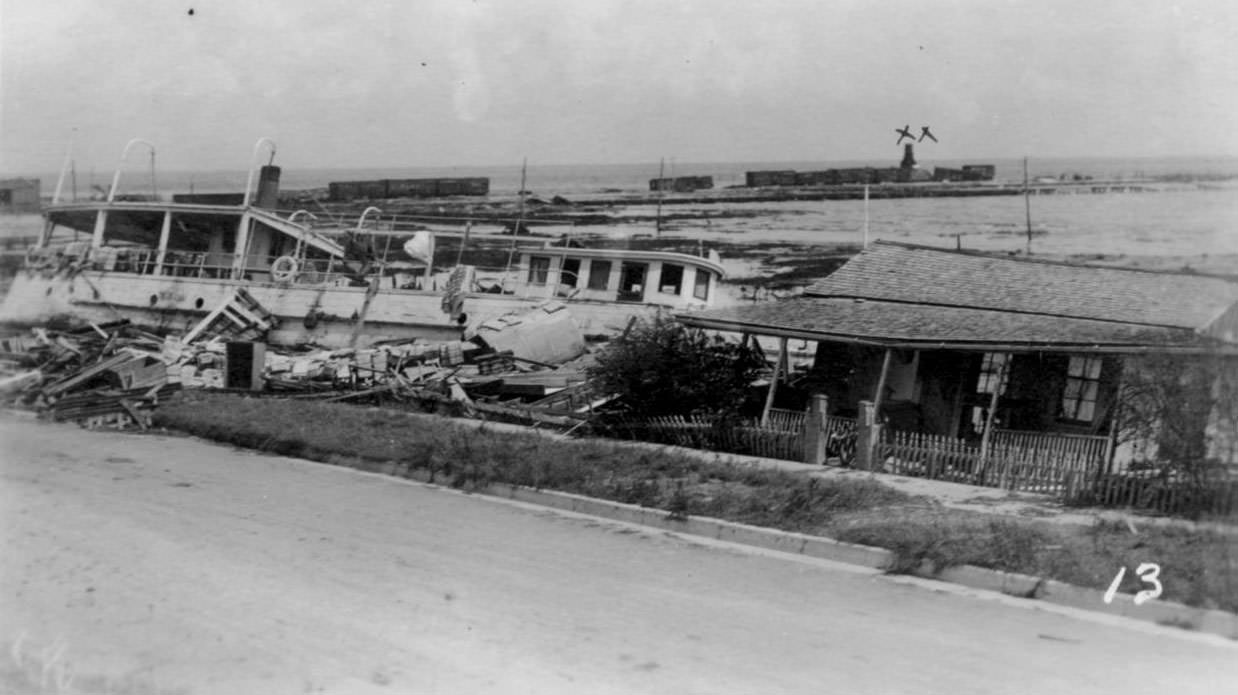 The Japonica wrecked on the shoreline. A small building stands precariously to the right, 1919