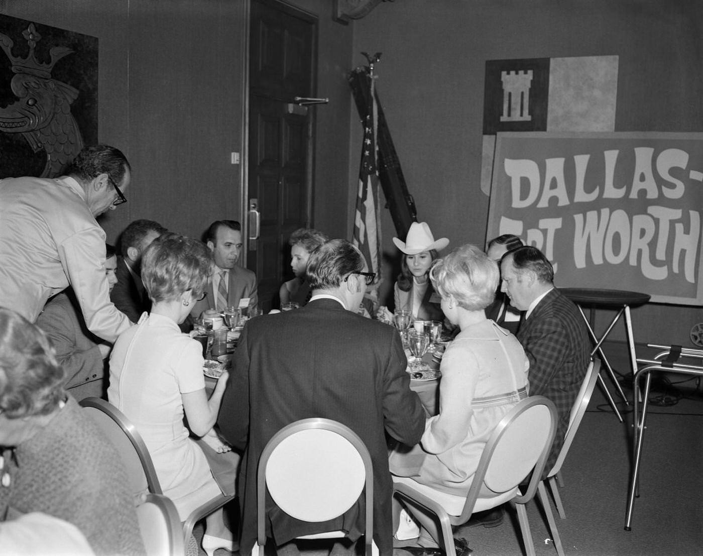 Men and women sitting around a table, and having a meal together, 1969. They are all dressed in formal attire and having conversations with one another.