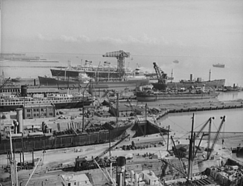 The fitting and repair slips at Newport News, Virginia. The S.S. America can be seen in the background. The ship in the adjacent slip is a tanker, 1941