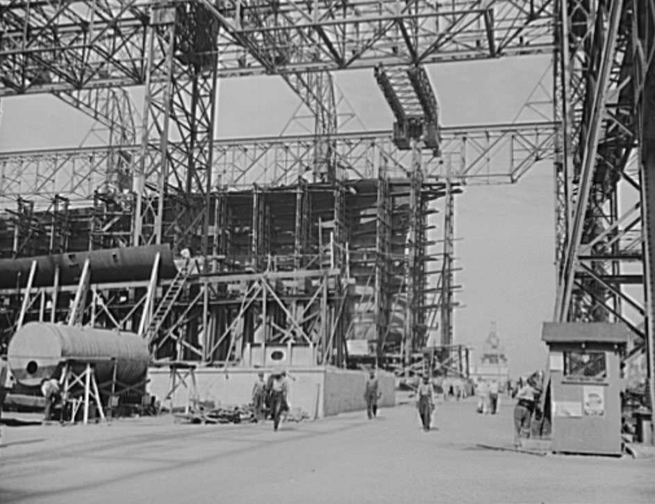 Through the scaffolding may be seen the prow of a battleship under construction, 1941