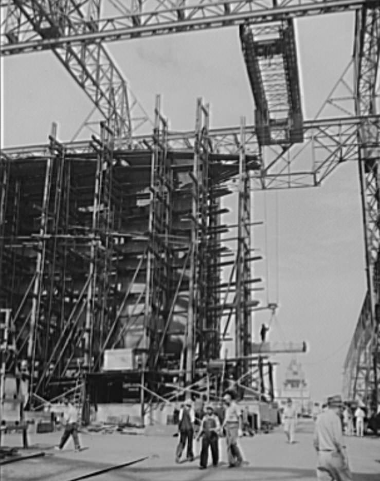 Through the scaffolding may be seen the prow of a battleship under construction, 1941