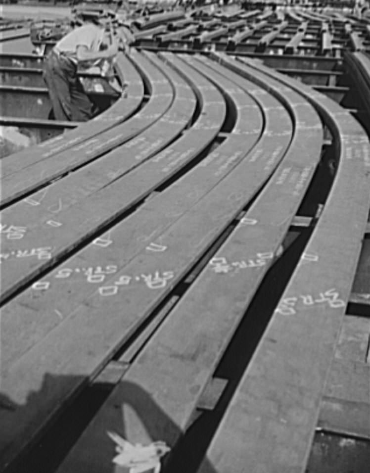 Thousands of workers contribute thousands of skills in the building of ships for Uncle Sam's growing Navy. This worker is topping punching holes on a ship's frame, 1941