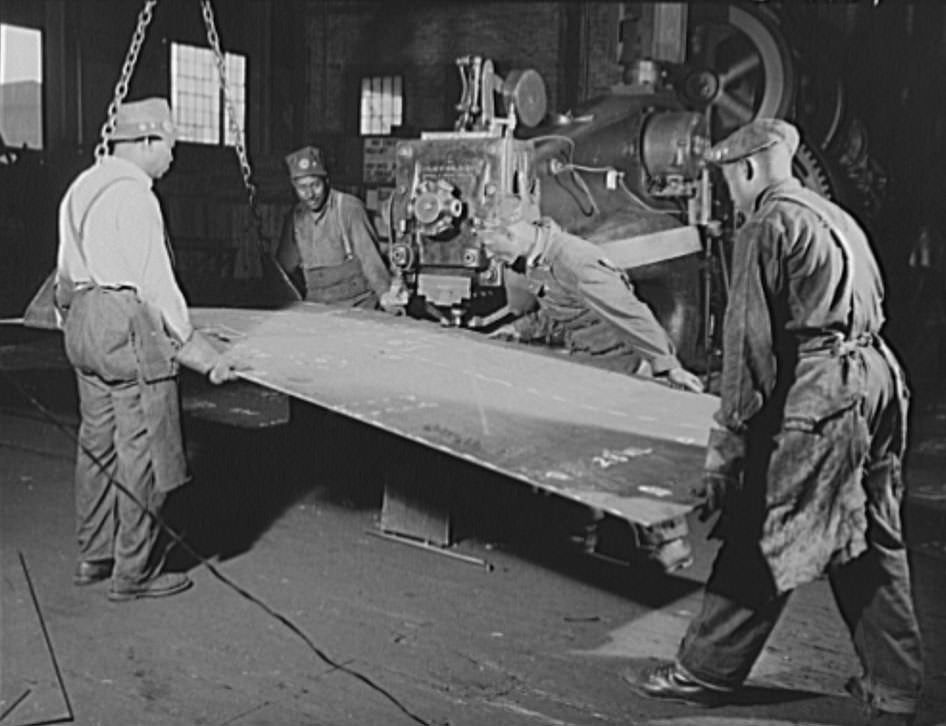 These four workers are guiding a steel plate through a punch press, 1941