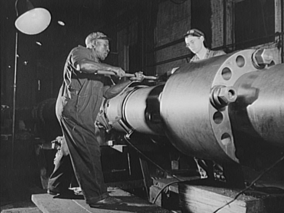 Skilled work requires brawn as well as brains. This husky navy yard worker is driving home a pin in the propeller shaft of a naval vessel under construction, 1941