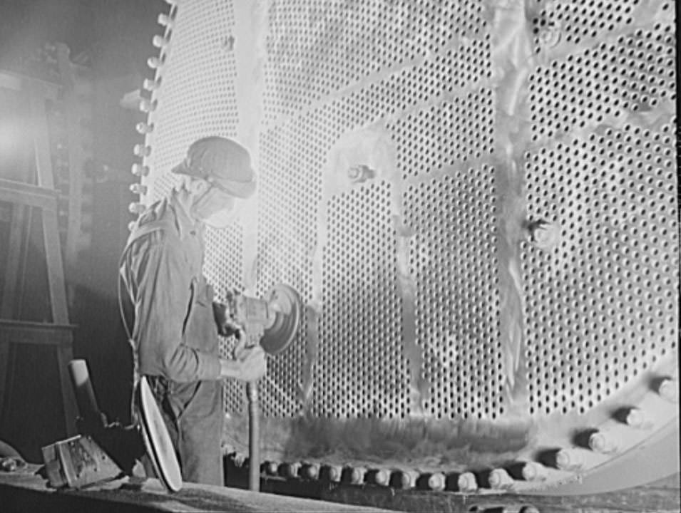 A worker is touching up one of the huge condensers for a U.S. Navy destroyer under construction, 1941