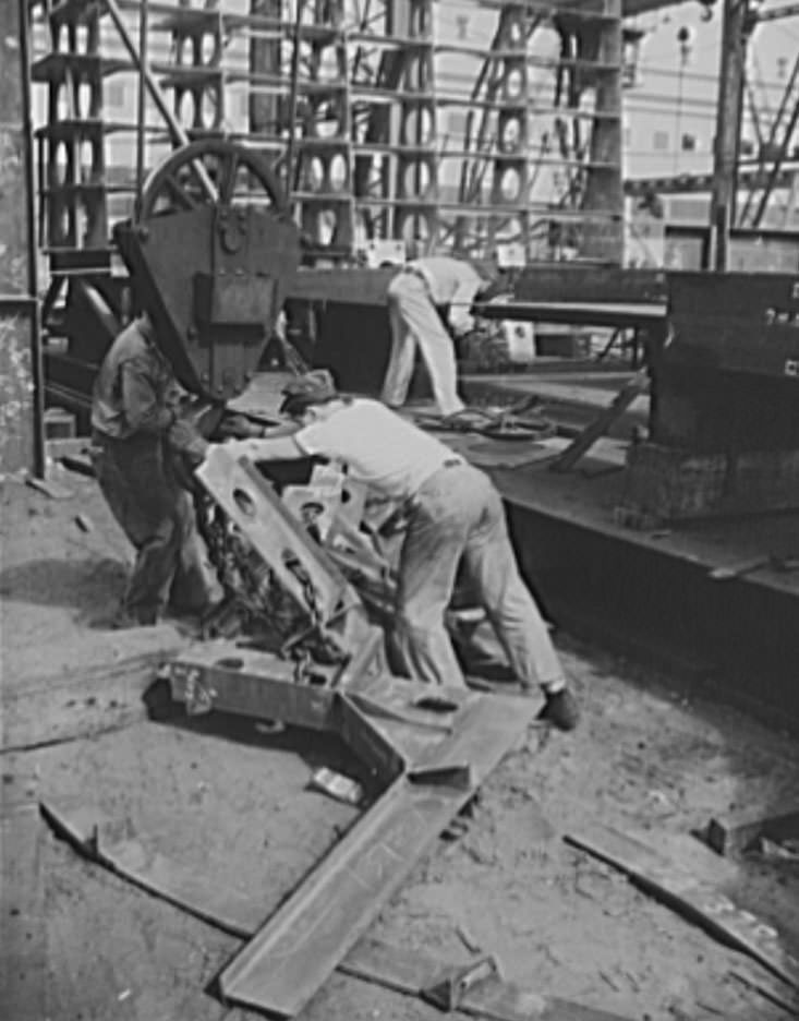 These workers are attaching parts for a new cruiser under construction to the overhead crane which will deliver the metal to the building ways, 1941