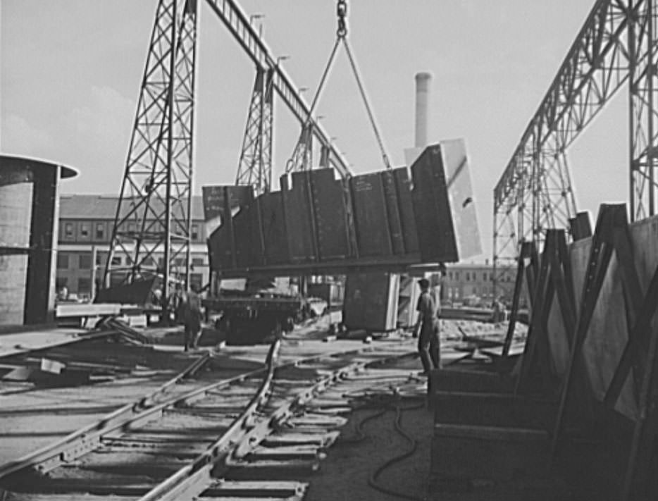 A section for a new U.S. Navy cruiser is being delivered by overhead crane to the building ways. Four cruisers and a battleship are under construction here, 1941