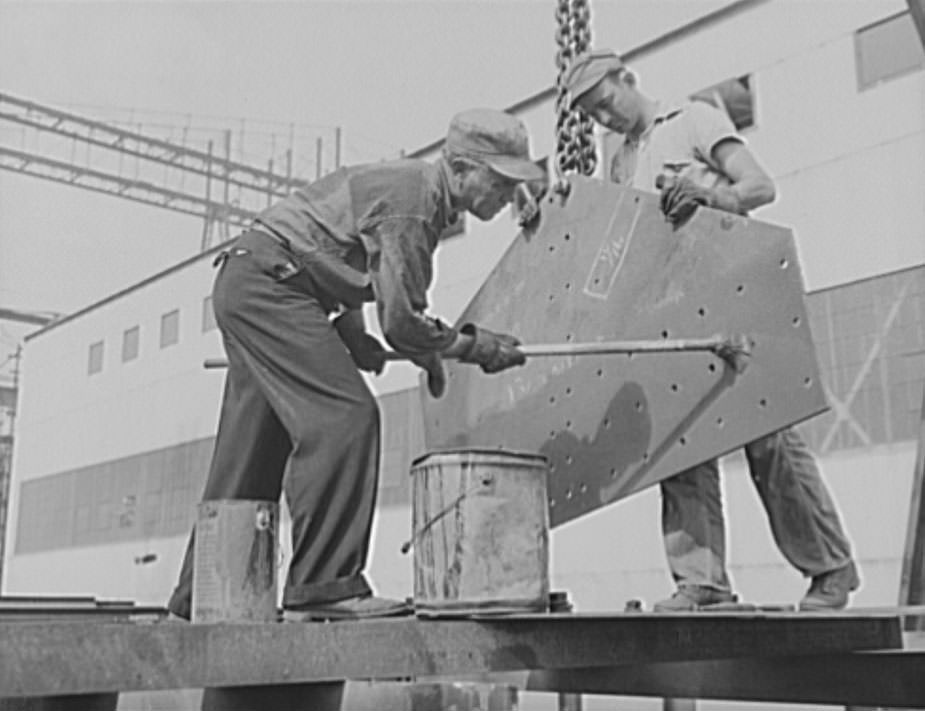 These workers are red-leading a plate, to prevent corrosion. Only the highest quality materials will serve for the new warcraft under construction for Uncle Sam's two-ocean fleet, 1941