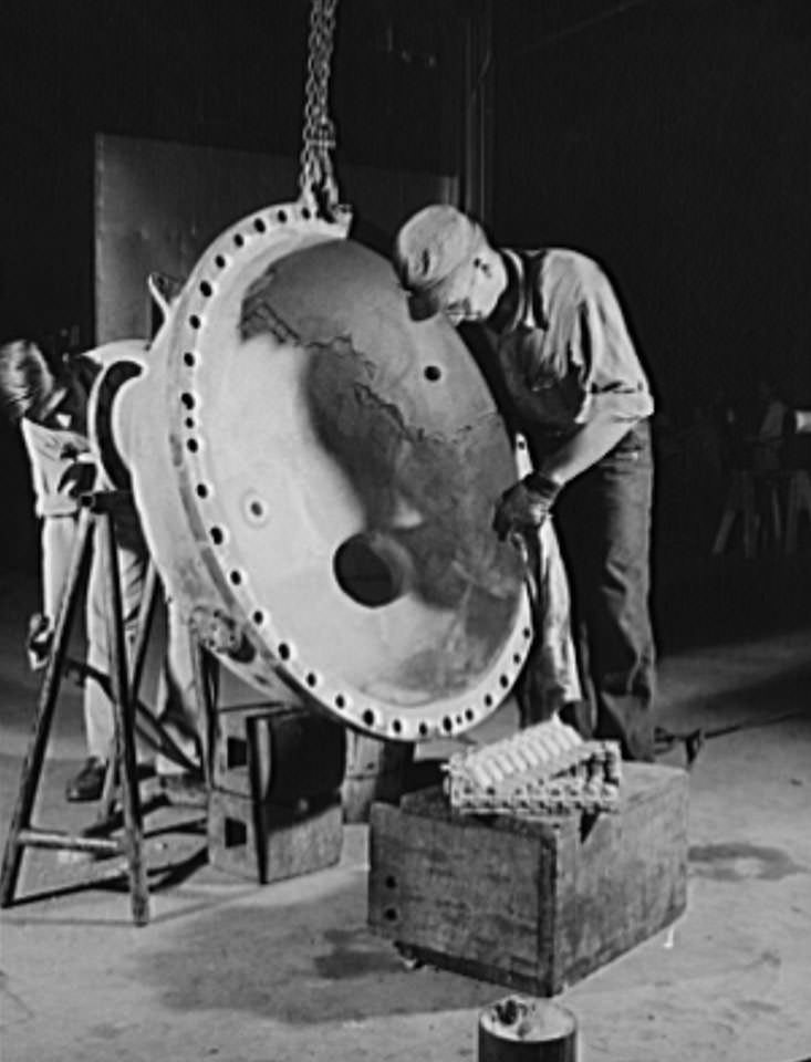 These skilled workers are tinpleting an evaporator top, part of a stream turbine which will help to drive a news naval vessel under construction at the Newport News, 1941