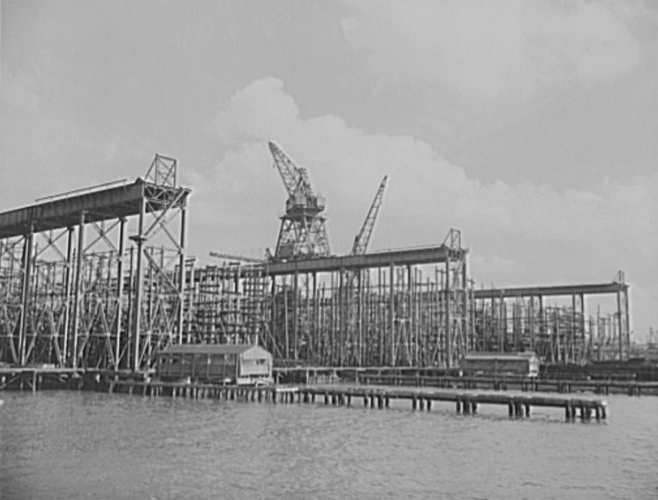 Thousands of tons of lumber and steel are used in the construction of these ways, where American mechanical genius is employed in the production of ships for our two-ocean Navy, 1941