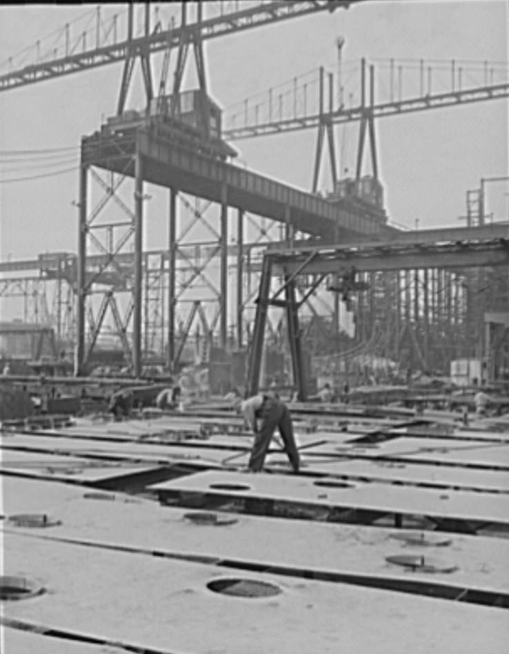 In the shadow of the huge building ways. where four cruisers and a battleship for Uncle Sam's growing navy are under construction, lies the ship's plate section, 1941