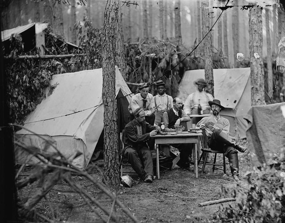 Officers of the 114th Pennsylvania Infantry playing cards in front of tents, 1864