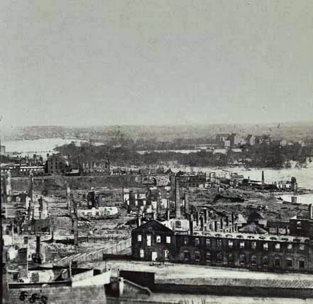 An aerial view of the "burnt district" in Richmond, taken from the old arsenal. The James River in background, 1865