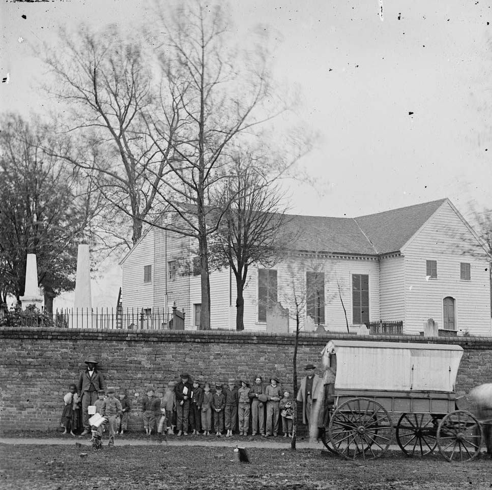 The main eastern theater of war, fallen Richmond, April-June 1865. This photograph shows African American man and little girl with white children in front of the church.