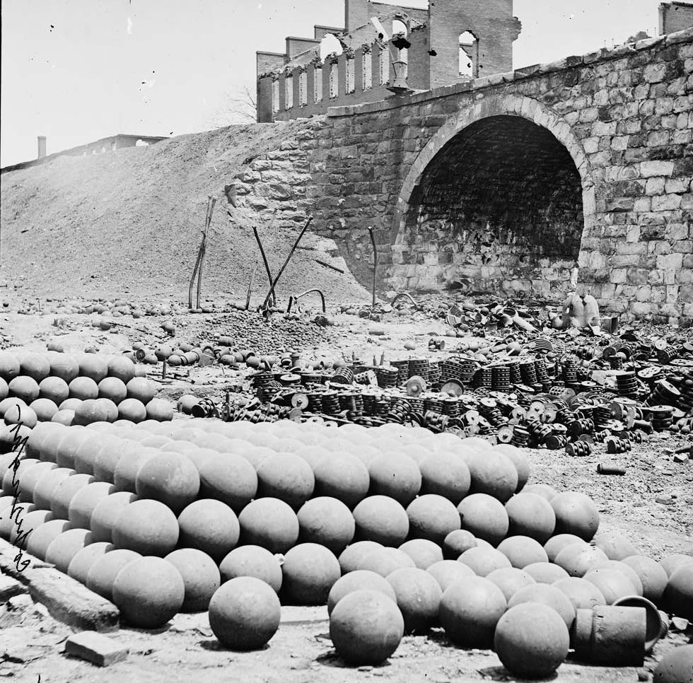Piles of solid shot, canister, etc., in the Arsenal grounds; Richmond & Petersburg Railroad bridge at right, 1864