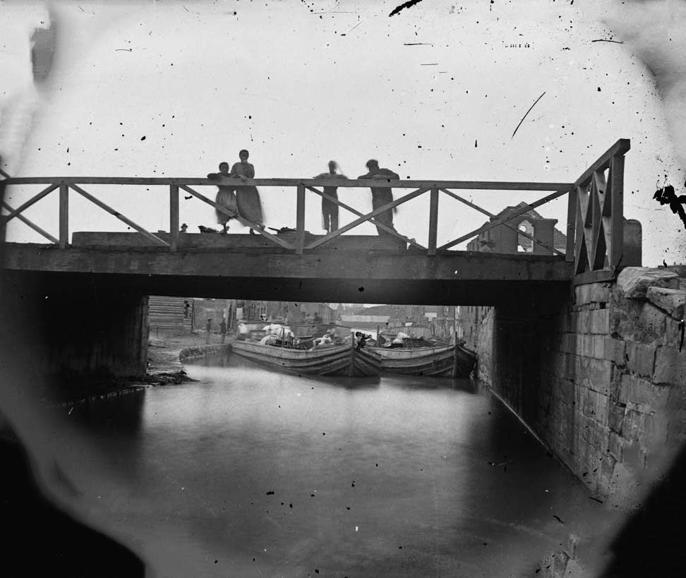 The main eastern theater of war, fallen Richmond, 1864. This photograph shows Canal Bridge at foot of 7th Street, Richmond. Shows African American children standing on the bridge.