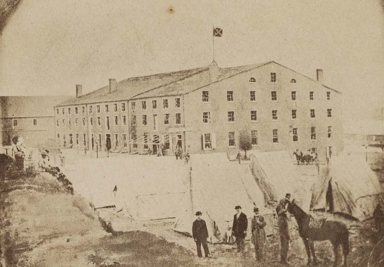 Men and a horse next to tents in front of Libby Prison, Richmond, Virginia, 1863