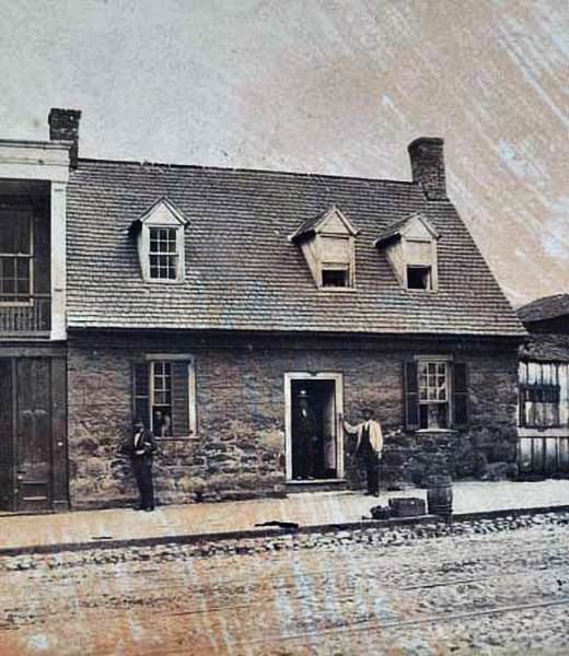 A group of men standing inside and outside of a stone house located at 1916 E. Main Street, Richmond, 1865