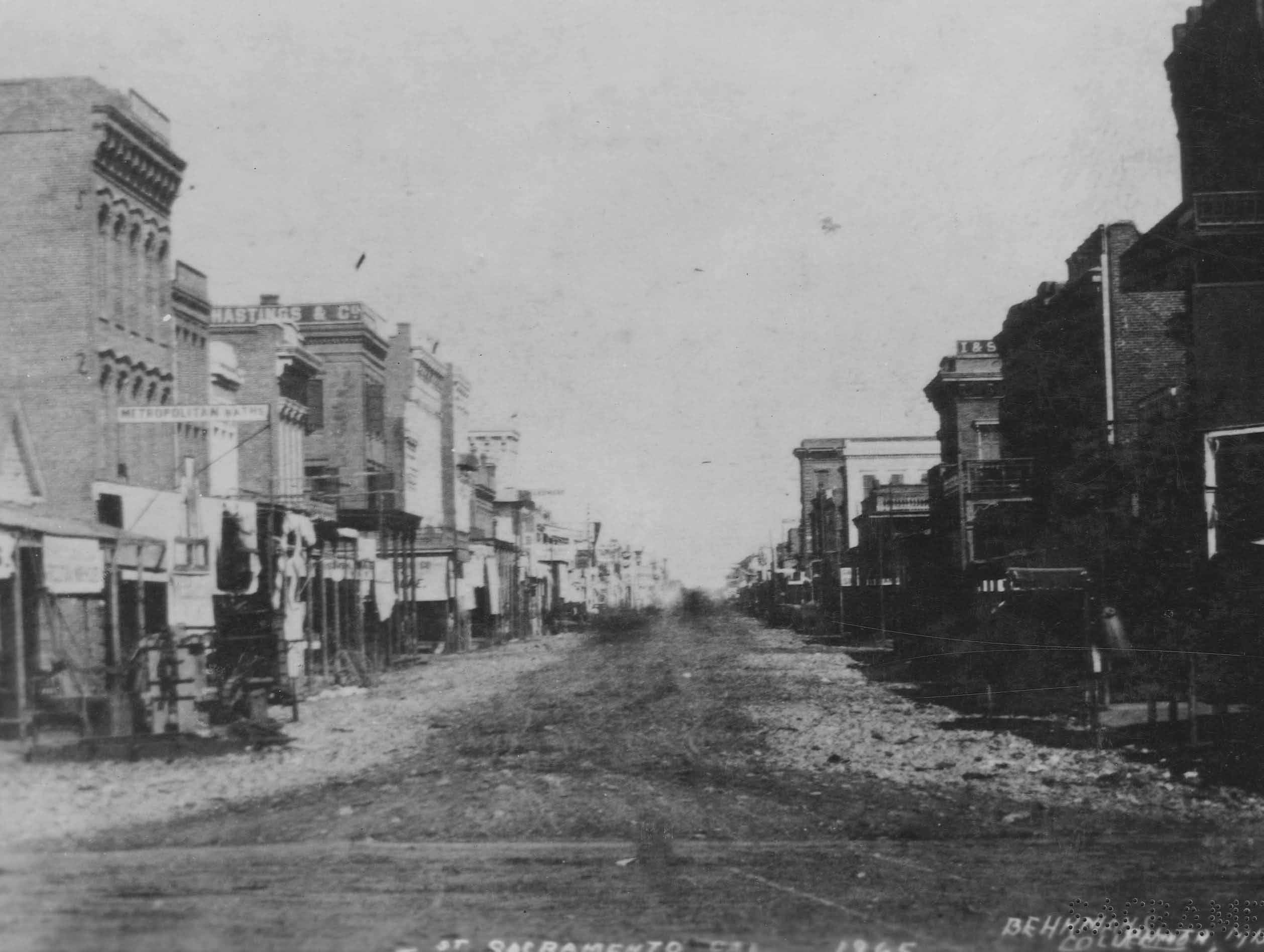 A view down J Street, showing, to the right, both the Metropolitan Baths and B.F. Hastings and Company, 1868