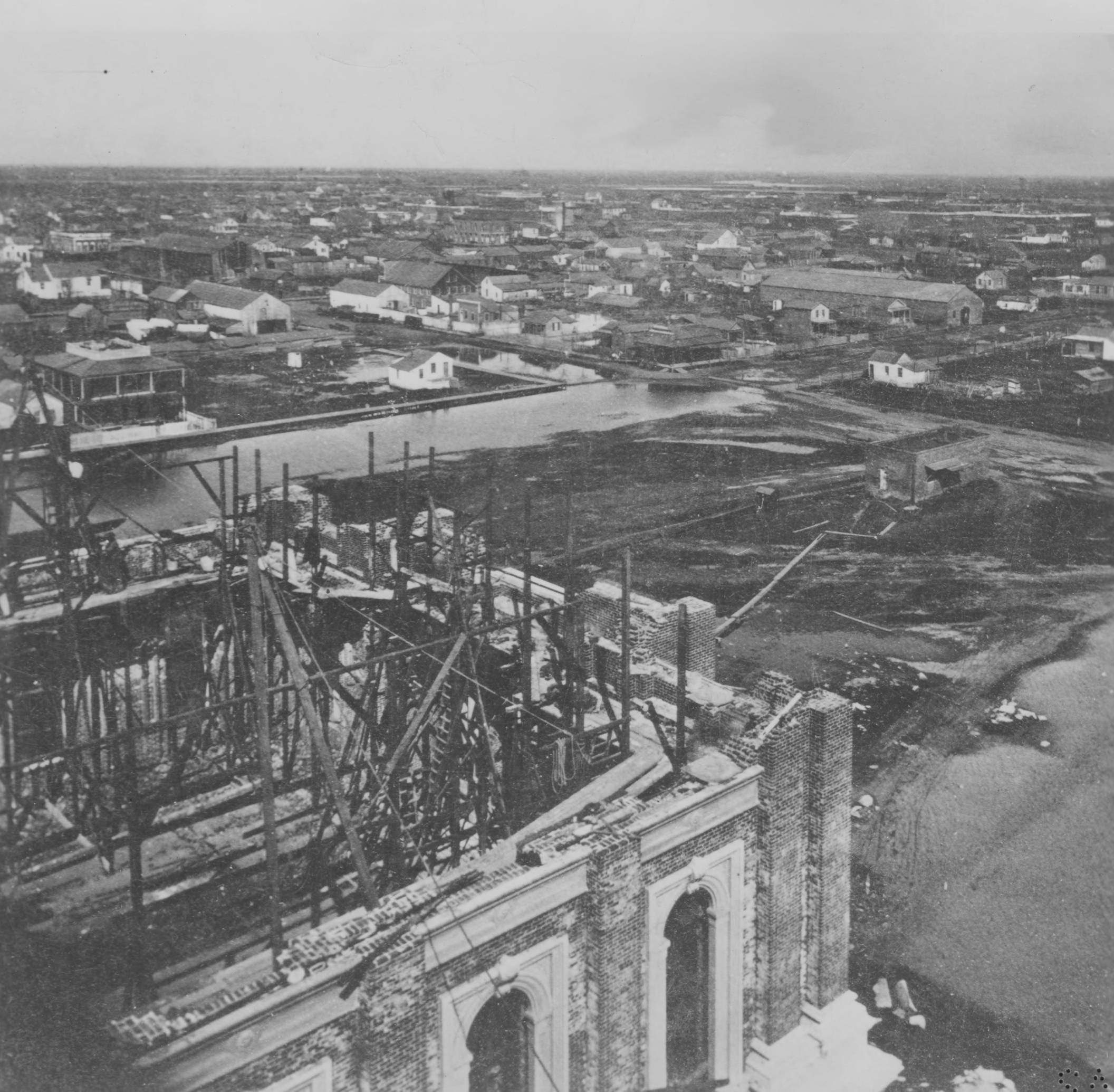 A rainy day in 1868 is viewed from on high upon the unfinished dome of the California State Capitol building. N Street and 12th Street intersect in the upper portion of the photograph.