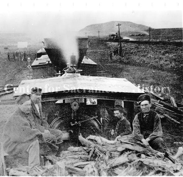 A group of men sitting by the woodpiles on the back of an engine, 1869