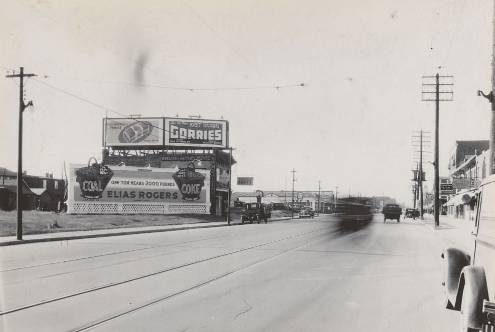 Billboard adjacent to a building at 1003 Danforth Avenue, near Donlands Avenue. Two more billboards bearing the company name De Luxe Advertising Company Limited, one advertising Gorrie's Chevrolet Oldsmobile and the other Purity Bread Limited, 1936