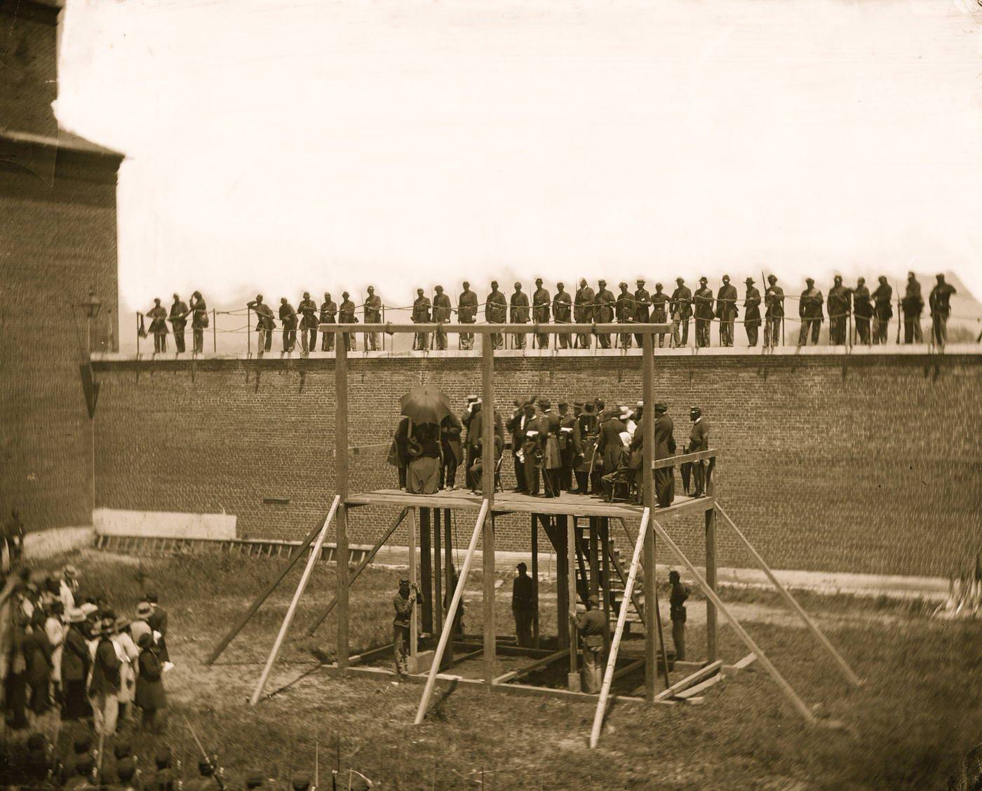 The four condemned conspirators (Mrs. Surratt, Payne, Herold, Atzerodt), with officers and others on the scaffold; guards on the wall, Washington, D.C., 1865