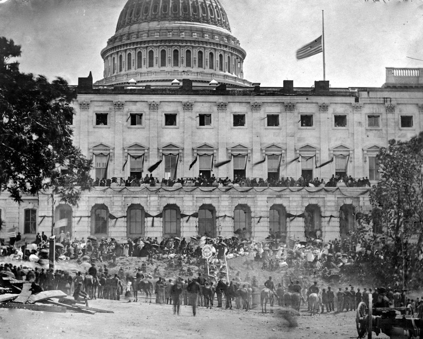 Spectators gather at the side of the Capitol, which is hung with crepe and flies the flag at half mast, during the "grand review" of the Union Army, Washington, D.C., 1865