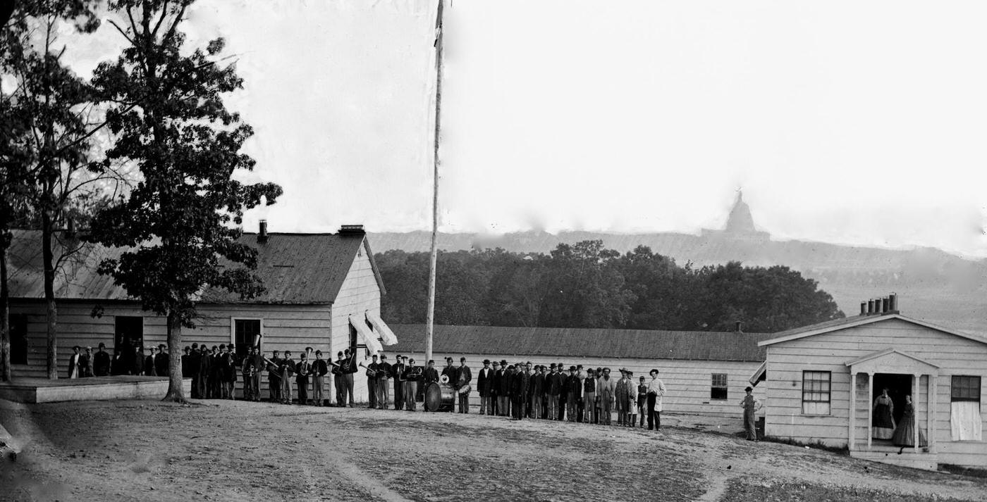 A military band standing before the officers' quarters at Harewood Hospital, located on the farm of WW Corcoran, at 7th Street Road near the Soldiers' Home, 1864.