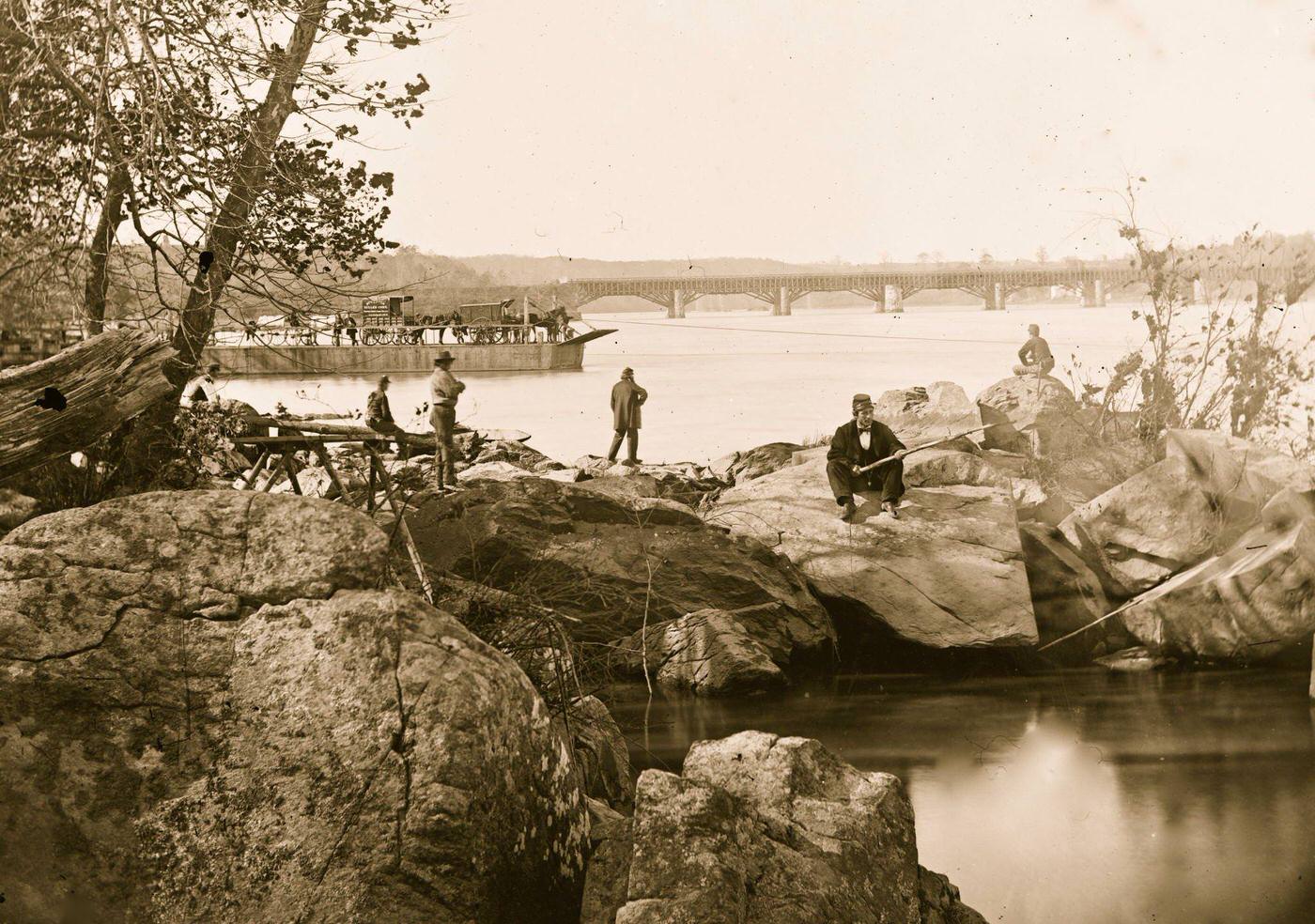 Georgetown ferry-boat carrying wagons, and Aqueduct Bridge beyond, from rocks on Mason's Island, 1863