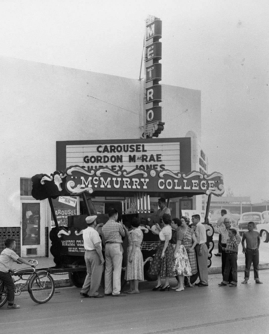 The McMurry College calliope on the street in front of the Metro Theater in Abilene with a group of people standing around it in the mid 1950's.