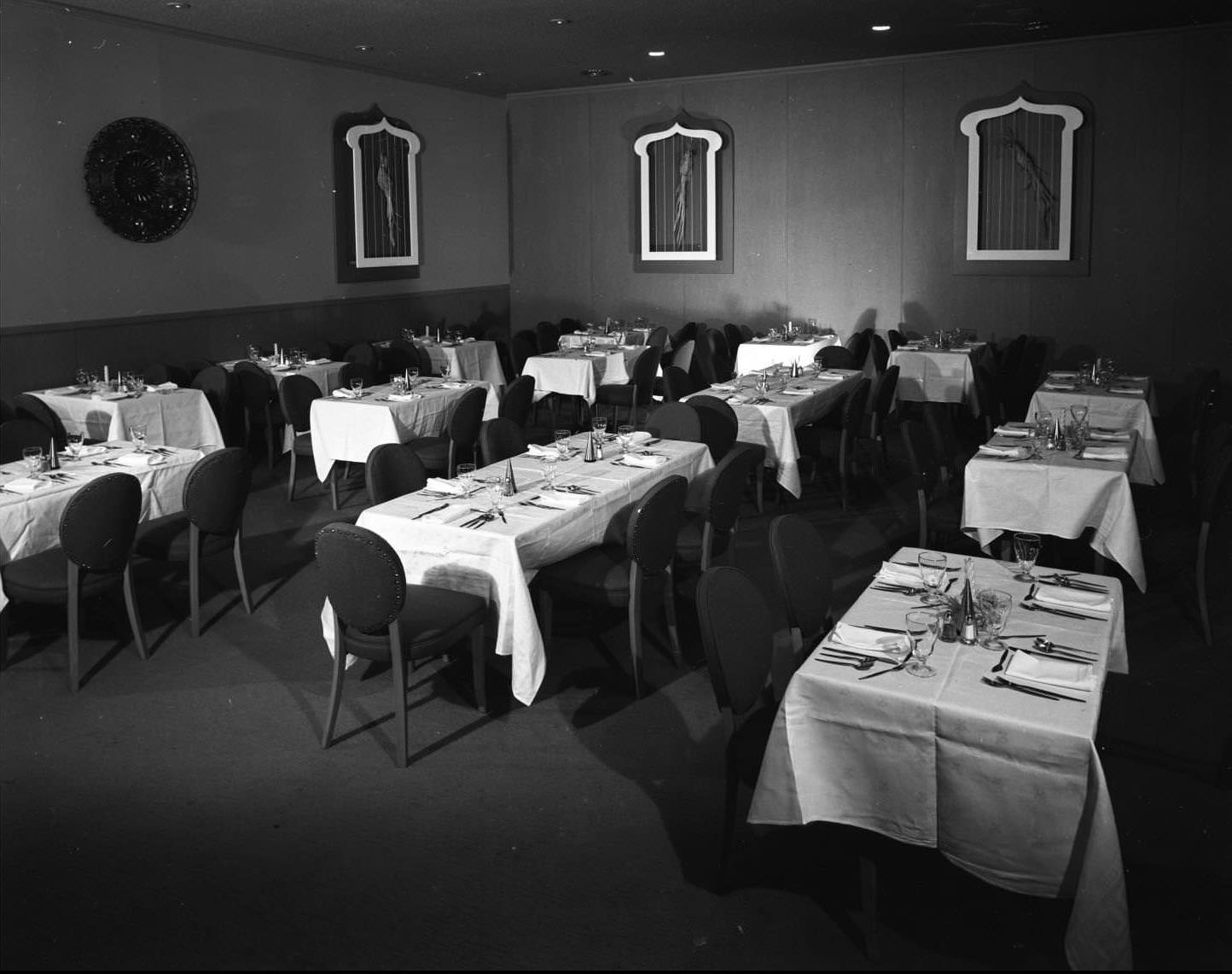 Paradise Room restaurant in the Sands Hotel, 1956. There are tables set for four or five people. There appears to be pictures of birds along the walls.