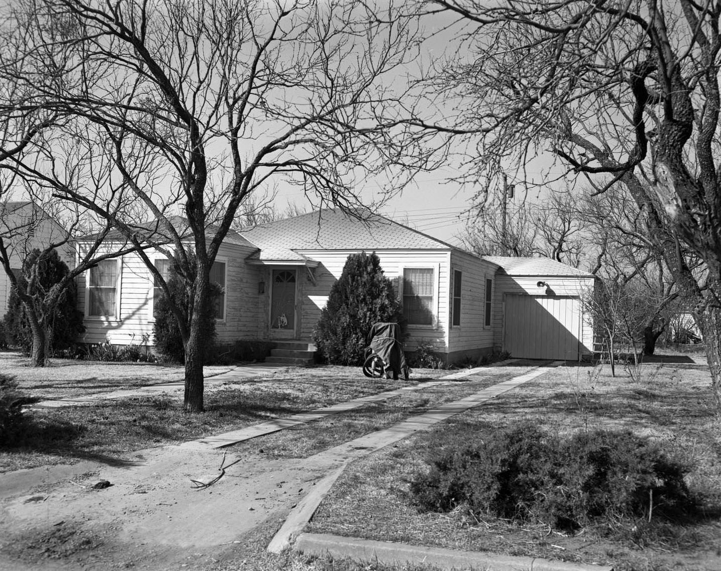 An exterior view of a wooden house with a garage, 1958