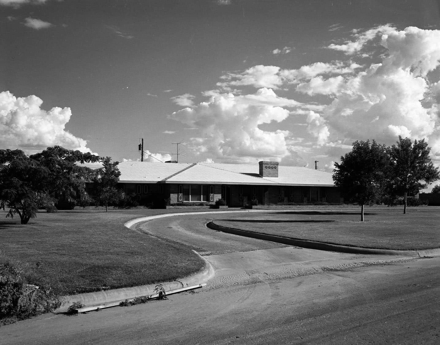 Expensive Homes on Leggett Drive, 1958. There are a two trees in the yard in front of the house and a few trees to the side of the house.