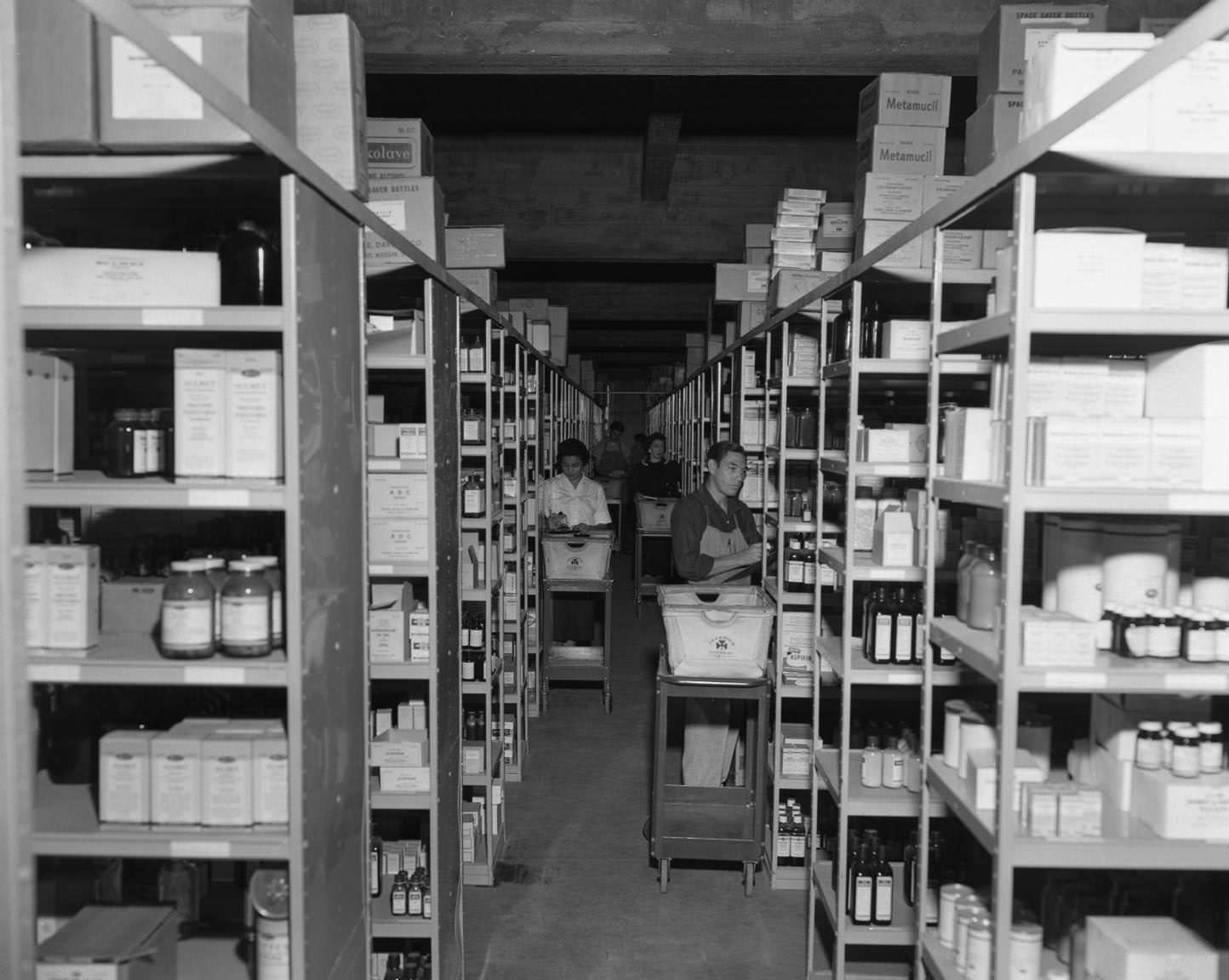 Employees loading shelves of medicine at Behrens Drug Co., 5th and Colorado, 1957