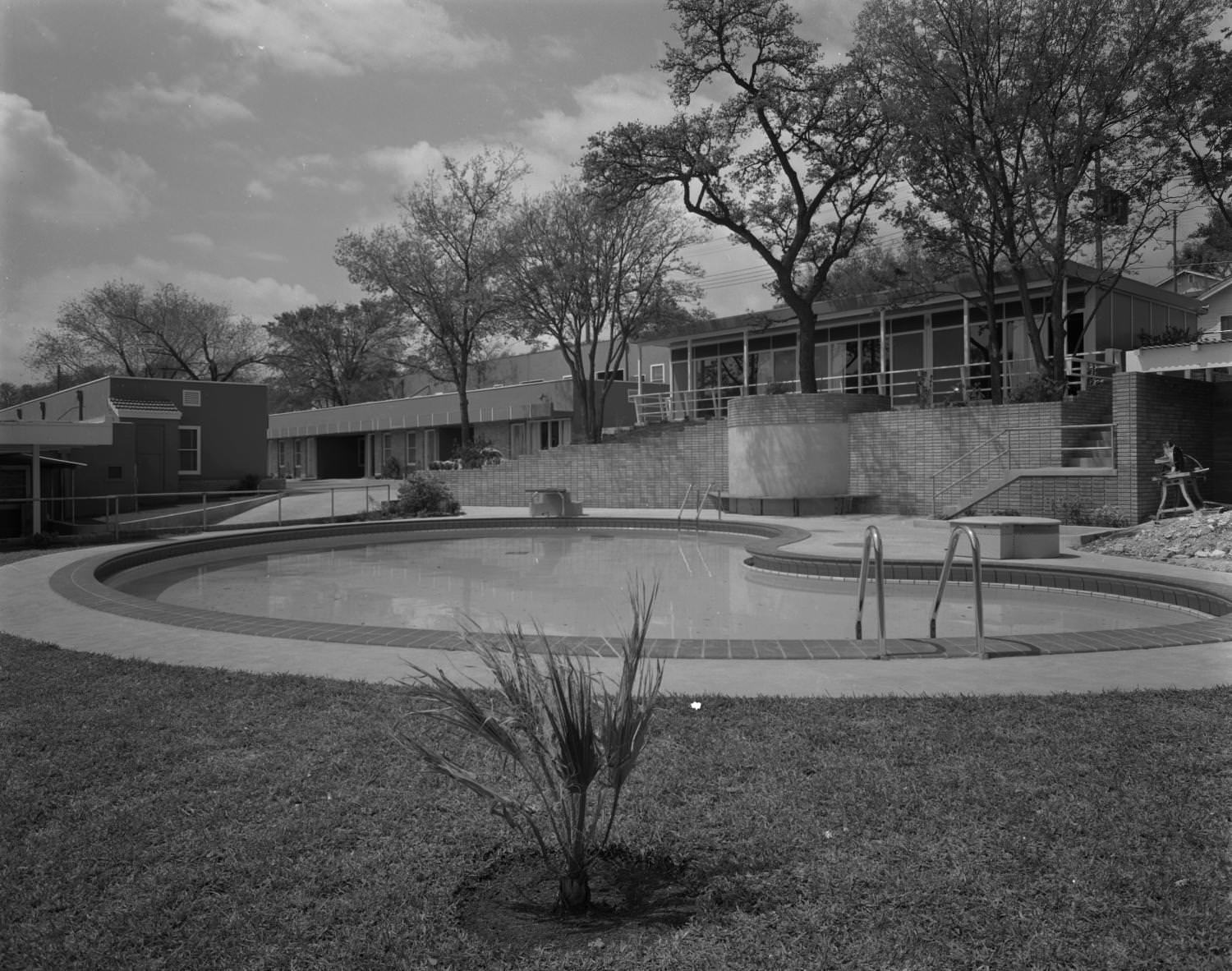 The exterior of Austin Motel, located at 1220 South Congress Avenue. There is a large swimming pool in front of the building, 1955