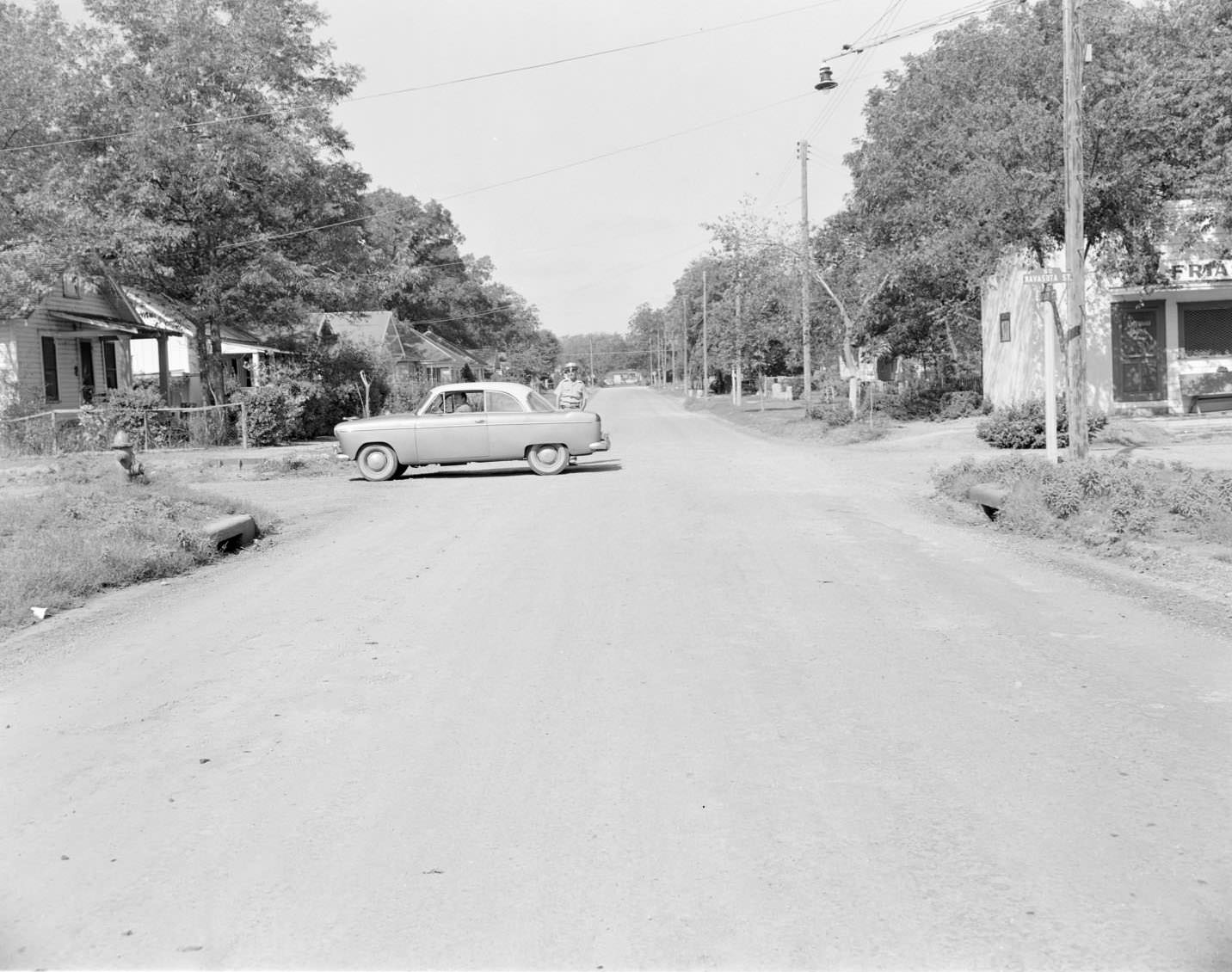 A car parked in the middle of the intersection of Navasota and Holly, 1954