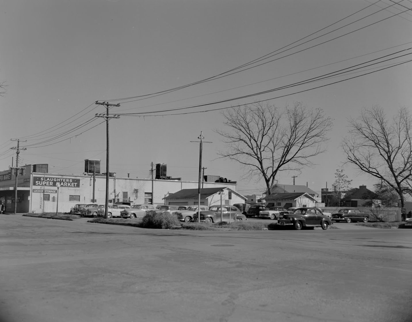 Cars in lot next to Slaughters Supermarket, 1958