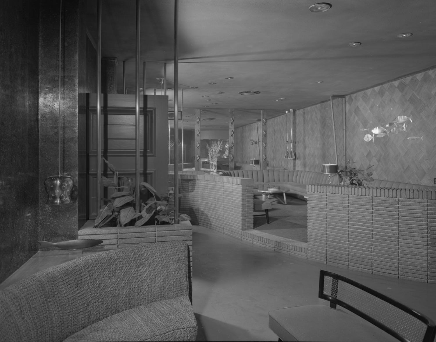 The Austin Club lounge with a seating area enclosed in a low brick wall, 1955