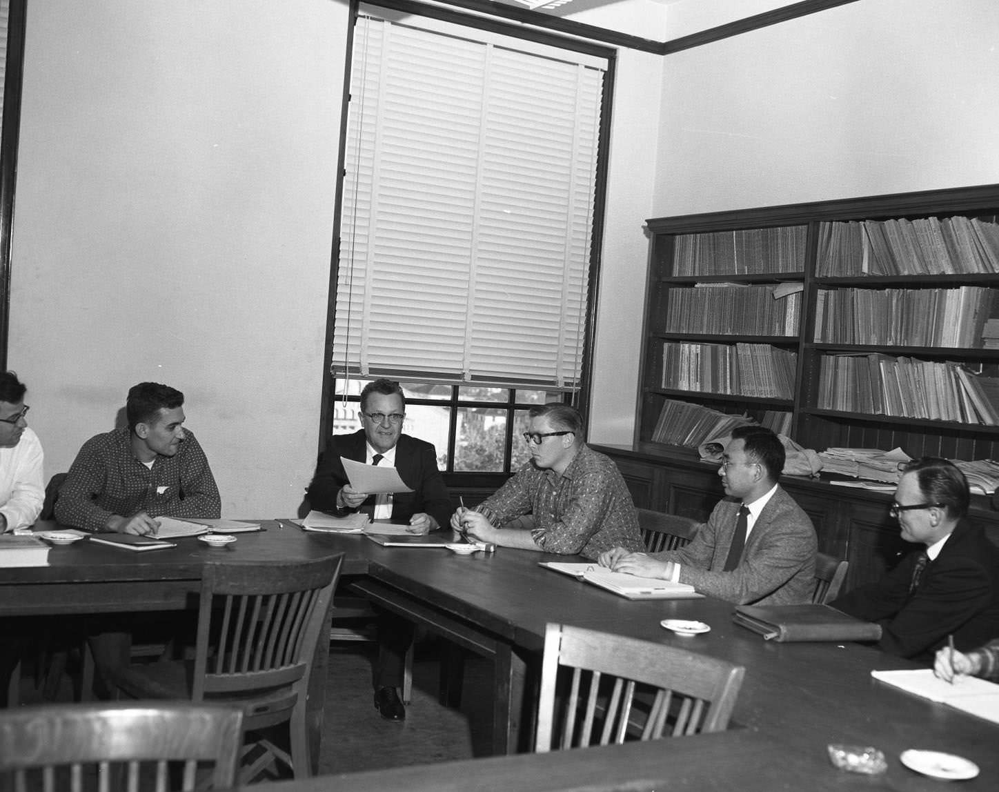 Men in discussion at table, probably administrators, 1958
