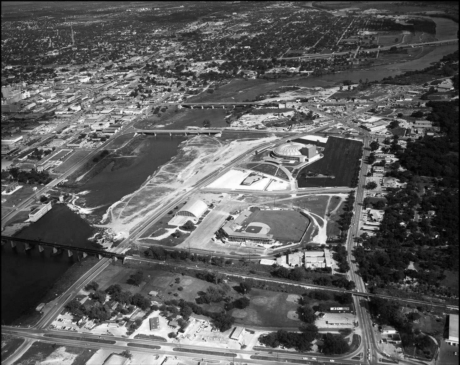 Aerial shot over Colorado River, looking east past Congress Ave. Bridge and Auditorium Shores, 1959