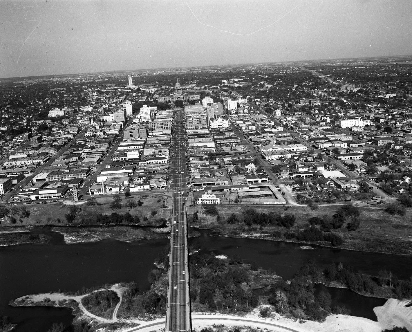 Aerial shot above the Congress Ave. Bridge and Colorado River looking directly north to Capitol, UT Tower in distance, 1959
