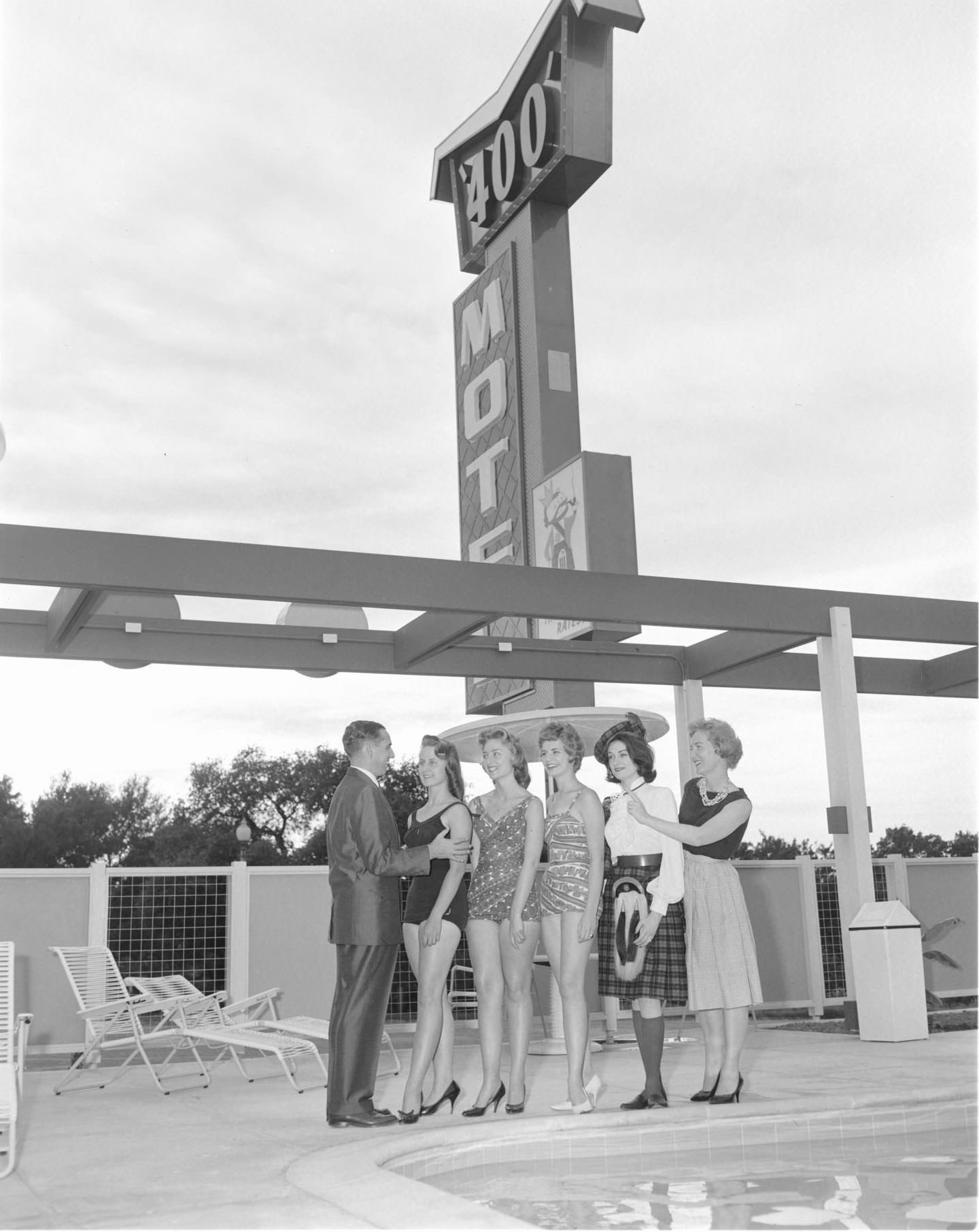 A man and five women near the pool of the Imperial 400 Motel, 1962.