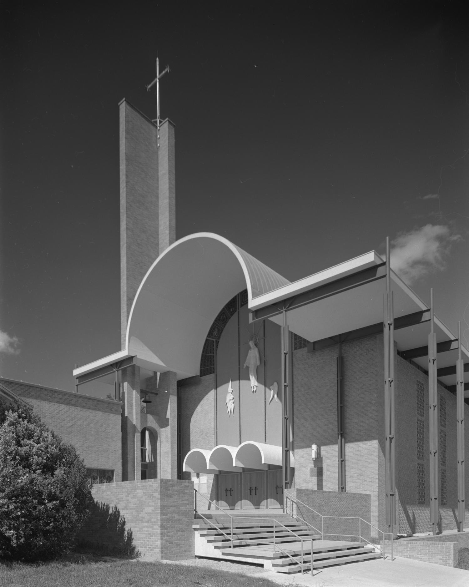 The exterior St. Martin's Lutheran Church that features and arched, geometric roof line a wide set of steps seen in the foreground, 1960
