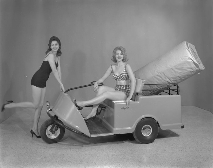 Two women posing to advertise a motorized cart for Powered Products of Texas, 1960