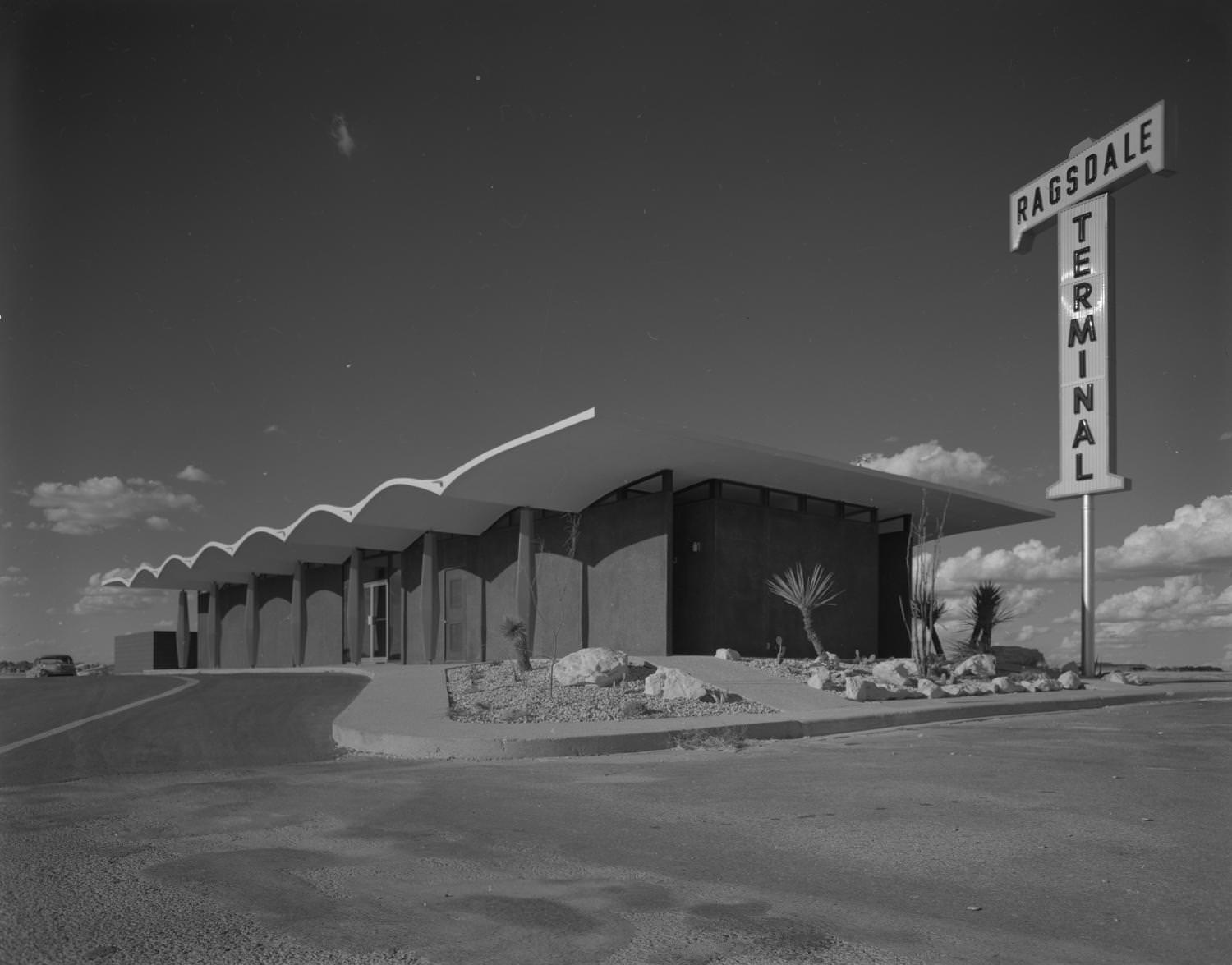 Ragsdale Terminal with an exterior facade that is dark with matching dark columns that can be seen on the left wall, along with a glass door entrance, 1962