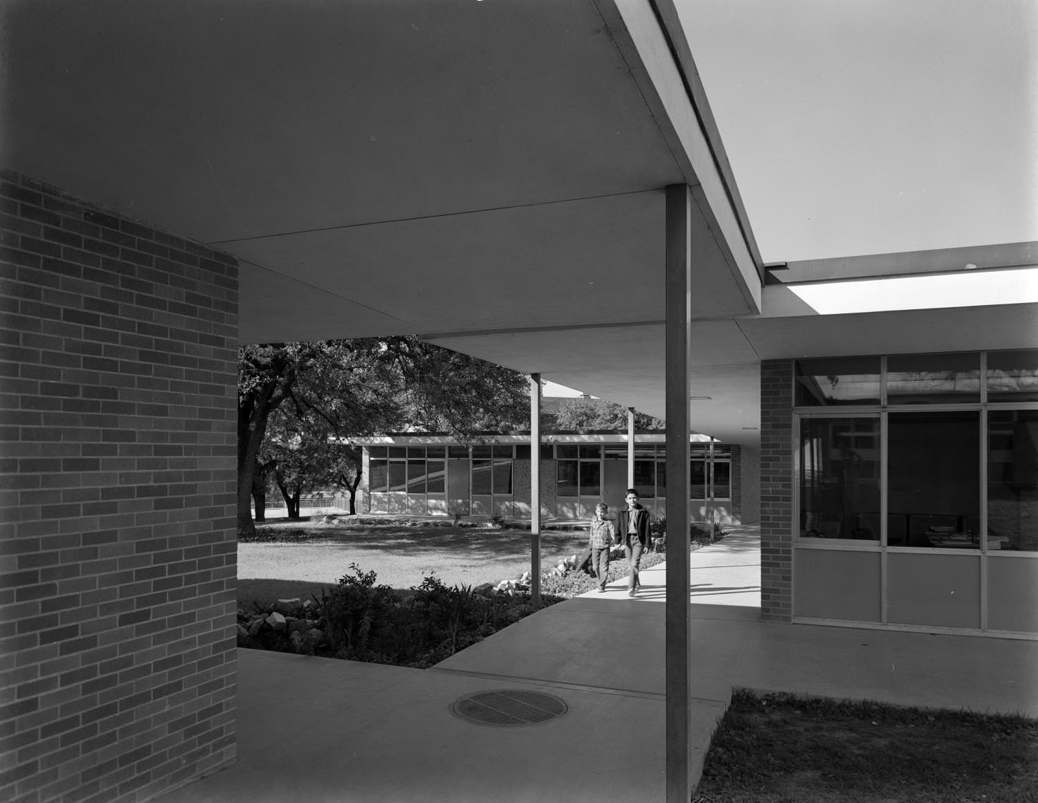 Two boys walking down a covered sidewalk at school, Austin, 1961