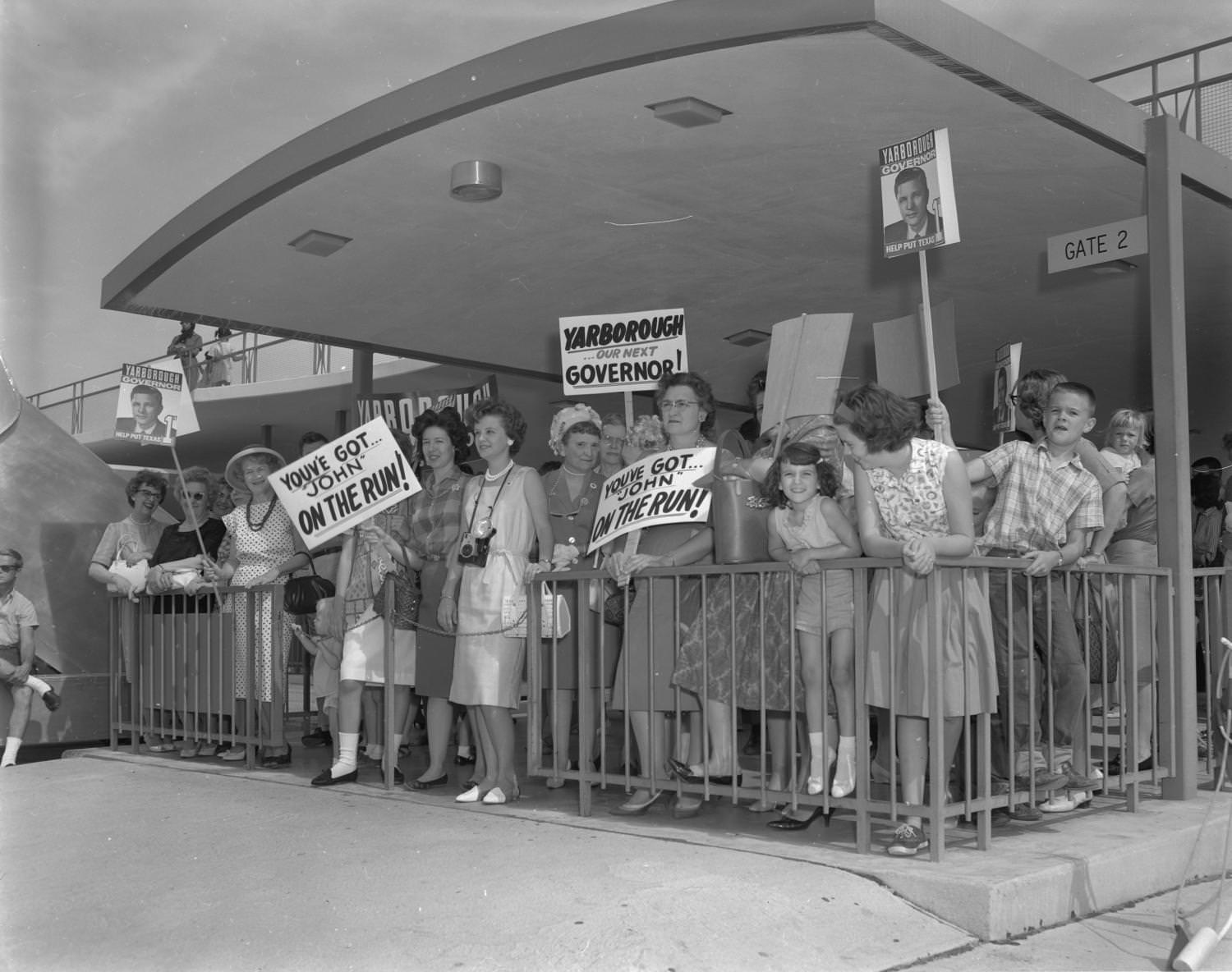 Supporters of gubernatorial candidate, Don Yarborough, standing with signs in a fenced area, 1962