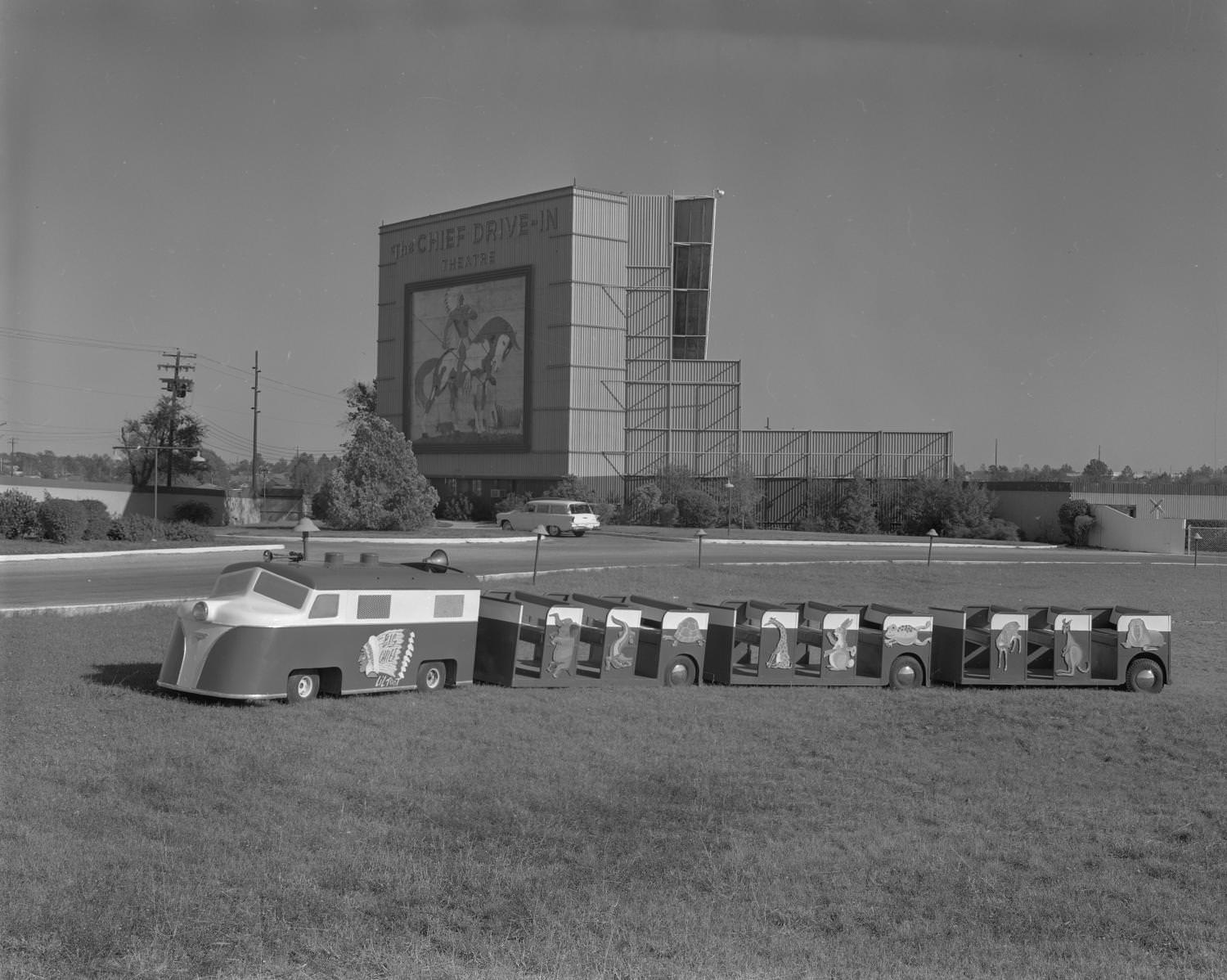 A mini children's' train parked in front of a Trans-Texas Theater that was located at 5601 North Lamar Boulevard, 1961